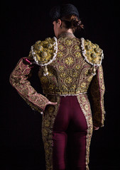 Woman bullfighter by dressing with vest on your back on a black background