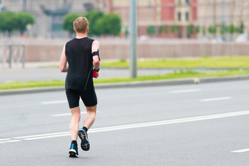Fototapeta premium Male athlete runs on a city road. Training