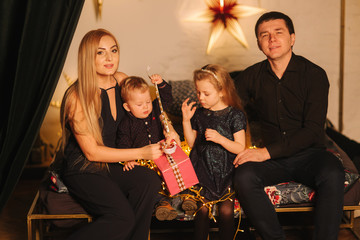 Christmas Family. Portrait of dad, mom, daughter and son sitting at home by the Christmas tree. Happy family. Christmas mood