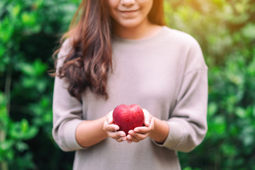 A beautiful woman holding a fresh red apple in hand