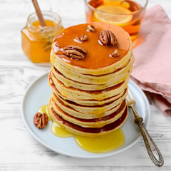 Sweet homemade stack of pancakes with honey and pecan nuts for Breakfast.