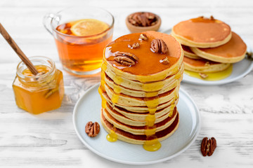 Sweet homemade stack of pancakes with honey and pecan nuts for Breakfast.
