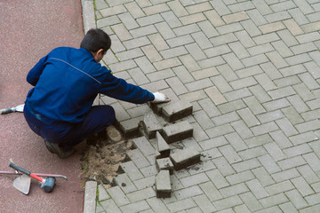 Repair of paving slabs. Worker mason shifts the pavement