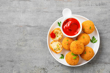 Homemade Fried Risotto Arancini stuffed with cheese, served with tomato sauce.