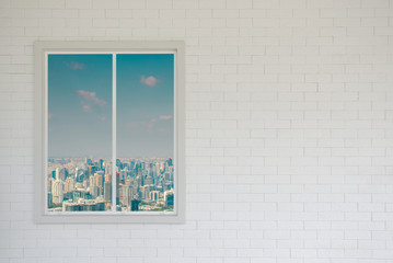 Blank brick wall in white and modern window with skyscraper view and sunlight