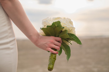 The bride holding bouquet of flower on the beach