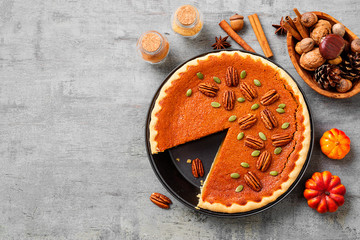 Festive Homemade Pumpkin Pie decorated with pecan nuts and pumpkin seeds.