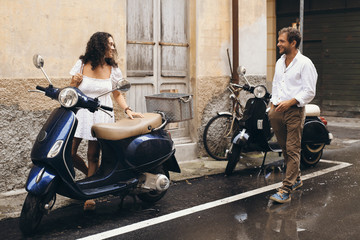 Beautiful young couple with a scooter in Italy