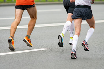 Fototapeta premium Legs of runners Marathon race on the city road. Group of runners. Muscle work