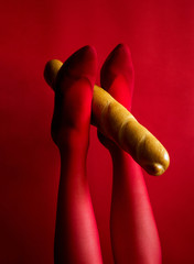 beautiful female legs in red tights hold a baguette with their feet up photo