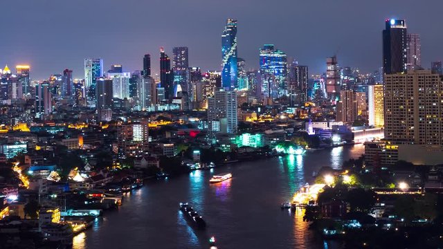 Time lapse view of Bangkok City at night and travel a boat trip on Chao Phraya River. High angle city background and Light Color in the capital Thailand Asia