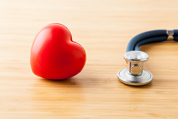 Healthcare and medical concept. Stethoscope and red heart on wooden table.