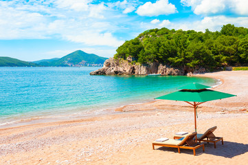 Beautiful beach with chaise lounges near Budva, Montenegro. Travel destination, popular touristic...