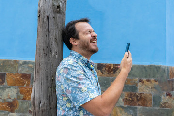 Frustrated hipster man feeling upset desperate, receiving social media news on the smart phone. Guy crying after read a message of an infidelity. Dramatic and suffering after get fired and rejected.