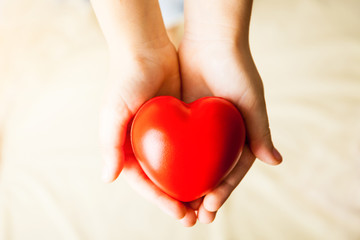 child hands holding red heart, health care, donate and family insurance concept