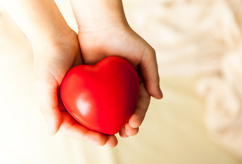 child hands holding red heart, health care, donate and family insurance concept