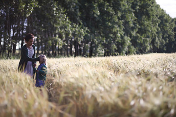 Naklejka na ściany i meble A young mother walk in wheat fields