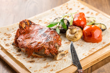 pork chop steak with grilled vegetables and champignon on lavash bread on wooden table