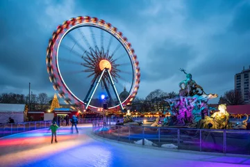 Fotobehang Kerstmarkt bij de Neptunus-fontein in Berlijn met reuzenrad en ijsbaan in de winter © eyetronic