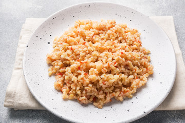 Boiled bulgur with tomatoes in a ceramic plate.