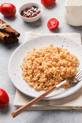 Boiled bulgur with tomatoes in a ceramic plate.