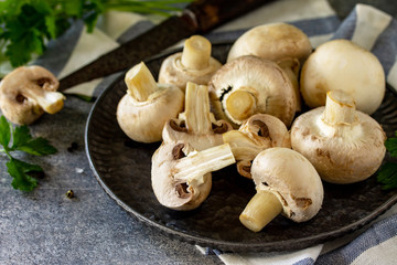 Champignons. Fresh white mushrooms in bowl on stone background. Free space for your text.