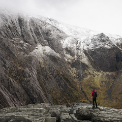 Naklejka premium Stunning dramatic landscape image of snowcapped Glyders mountain range in Snowdonia during Winter with menacing low clouds hanging at the peaks