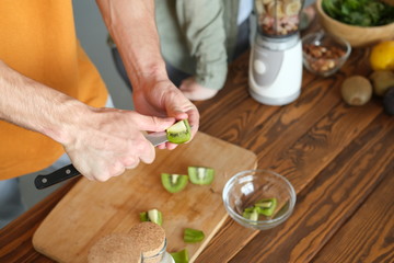 Obraz na płótnie Canvas Man cuts kiwi for smoothie. 