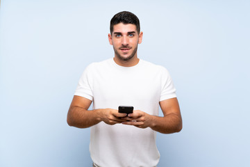 Caucasian handsome man over isolated blue background sending a message with the mobile
