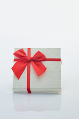 White gift box with red ribbon bow on white