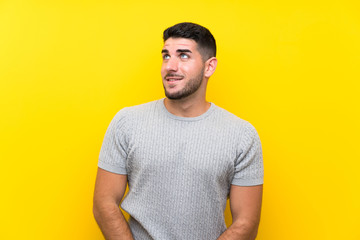 Young handsome man over isolated yellow background laughing and looking up