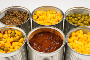 Canned food on white background. Green pea, beans, corn, lentils.