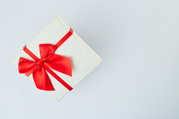 White gift box with red ribbon bow on white
