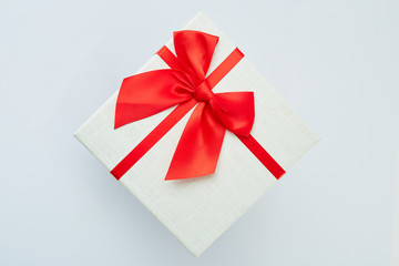 White gift box with red ribbon bow on white