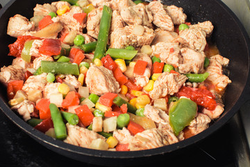 Roasted soft chicken pieces with vegetable mixture in pan.