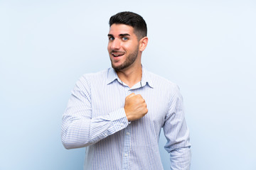 Caucasian handsome man over isolated blue background celebrating a victory