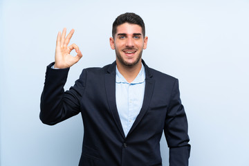 Handsome man over isolated blue background surprised and showing ok sign