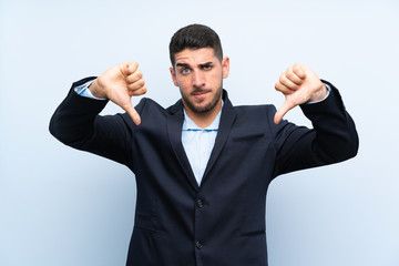 Handsome man over isolated blue background showing thumb down