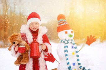 Child is making a snowman in snowy winter.
