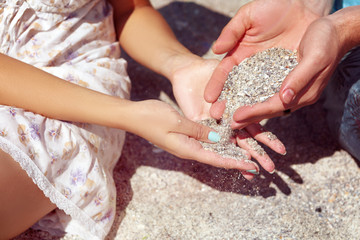  A couple is playing with sand on the beach. Close view