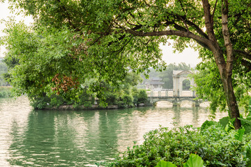 Fototapeta na wymiar Lake among green trees and scenic glass bridge in Guilin