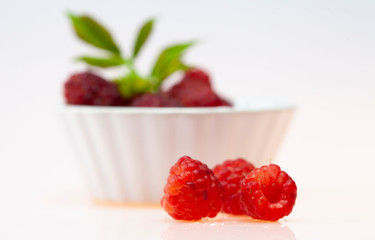 close up of raspberries in small cup over the white background, food close-up of fruits