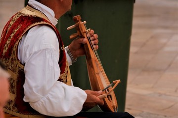 croatian street musican in tradional costume playing a typical Dalmatian lute called Lijerica in Dubrovnik