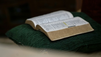 Open bible on green pillow with dark background