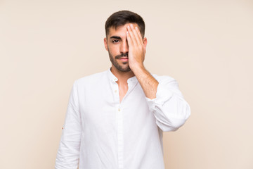 Handsome man with beard over isolated background covering a eye by hand