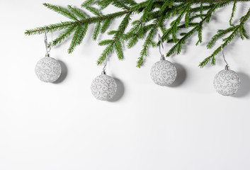 Christmas border of natural spruce branches, white with silver ornament balls on a white background. Flat lay, top view, copy space. Christmas background