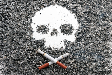 Two crossed bone-shaped cigarettes lie next to a skull formed by tobacco ash. Concept: smoking is...