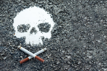 Two crossed bone-shaped cigarettes lie next to a skull formed by tobacco ash. Concept: smoking is...