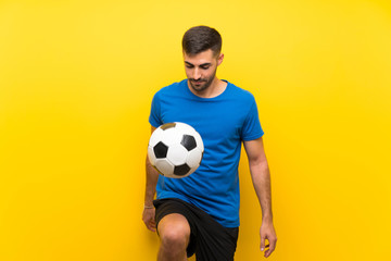 Young handsome football player man over isolated yellow wall