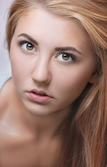 Obraz premium Portrait of a young blonde girl in a gray tank top